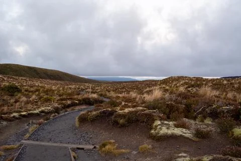 Winding Path Through Rugged Landscape Under Cloudy Sky Stock Photos