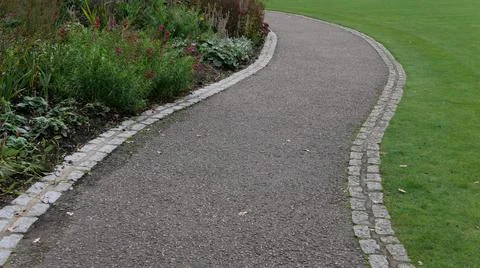 Winding pathway with plants on one side and lawn on other Stock Photos