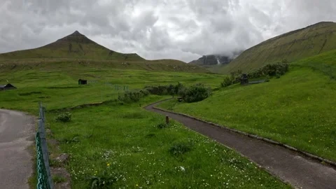 Winding pedestrian pathway through green meadows in Gjógv village, Faroe Islands Stock Footage 340026888