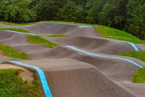 Winding Pump Track With Blue Lines And Forest Backdrop Stock Photos