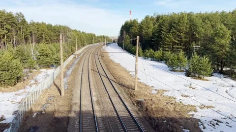 Winding railway tracks through pine forest with melting snow Video stock 330405585