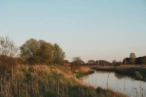 Winding River Flowing Through Lush Green Grassy Embankment at Sunset with S.. Stock-Fotos