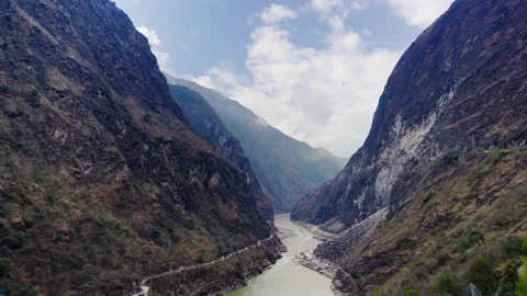 Winding River Through Rugged Mountain Gorge with Scenic Cliffs and Valley Road Stock Footage 312485674