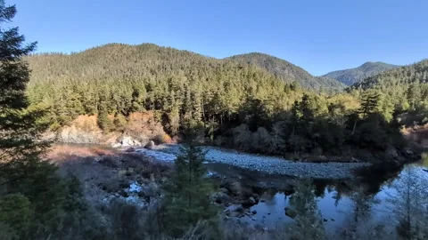 A winding river with whitewater rapids flows past rocky banks and trees Stock-Footage 326843266