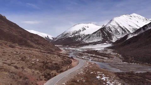 Winding road and river below snowy peaks in western China, aerial view Stock Footage 341842280