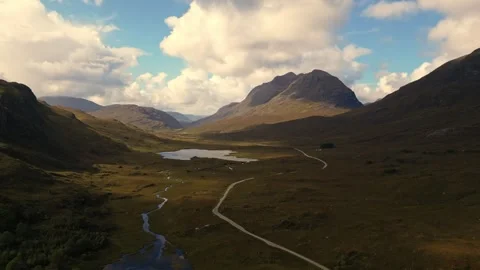 Winding Road and River Through Scottish Highlands Valley Under Dramatic Cloudy Stock Footage 348089795