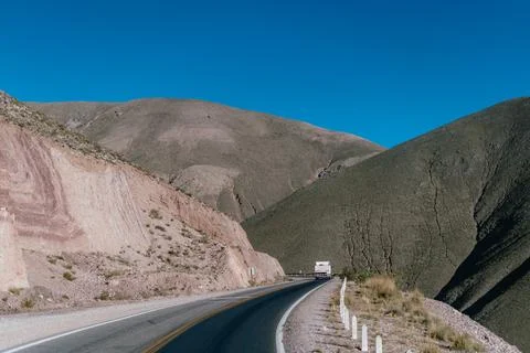 Winding road cuts through rugged, arid mountains Stock Photos