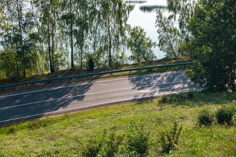 Winding road lined with trees. The road is empty. The trees, birch trees, are Stock Photos