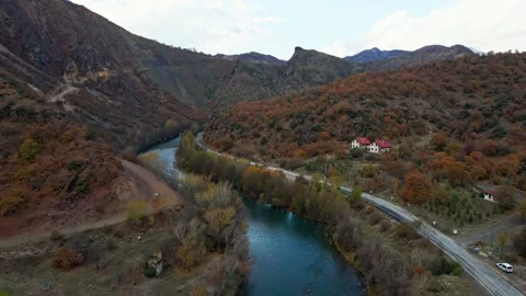 A winding road runs through a valley with a river running alongside it Stock Footage 327907547