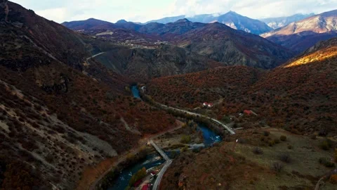 A winding road runs through a valley with a river running alongside it Stock Footage 327907595