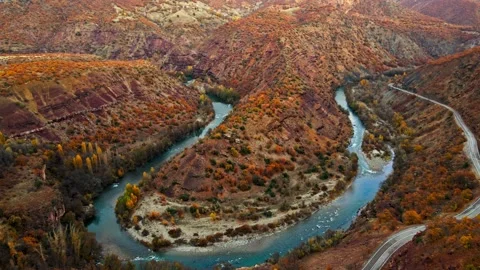 A winding road runs through a valley with a river running alongside it Stock Footage 327907644