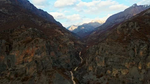 A winding road runs through a valley with a river running alongside it Stock Footage 327907679