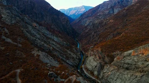 A winding road runs through a valley with a river running alongside it Stock Footage 327907717