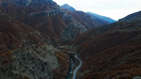 A winding road runs through a valley with a river running alongside it Stock Footage 327907756