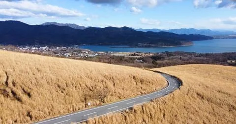 A winding road snaking through a grassy hilltop Stock Photos