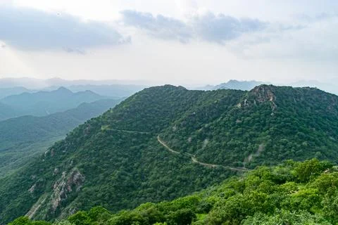 Winding road stretching through lush green aravalli mountain range in india Stock Photos