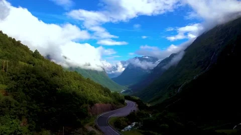 Winding road through a green valley beneath mountain peaks Stock-Footage 341328825