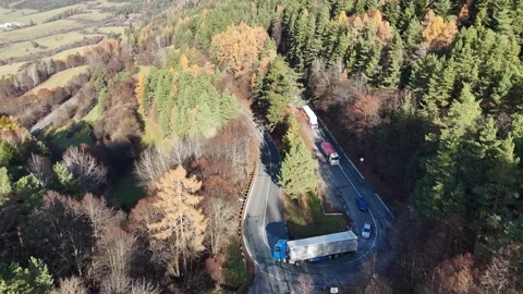 Winding road through a hilly forest, with a blue truck just taking a sharp turn. Stock Footage 328627908