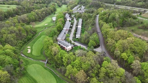 Winding road through lush forest passes residential buildings, revealing Stock Footage 311771325