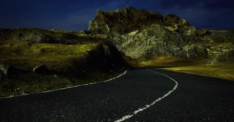Winding road through mountainous terrain under night sky with rocky formation 스톡 일러스트