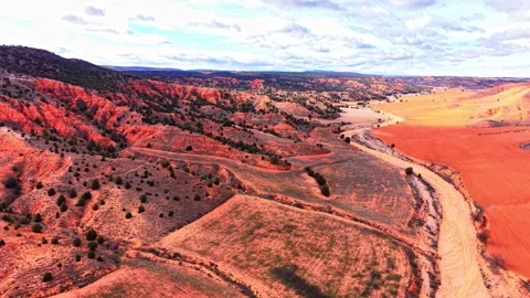 Winding road through red earth hills and green fields Video stock 334861831