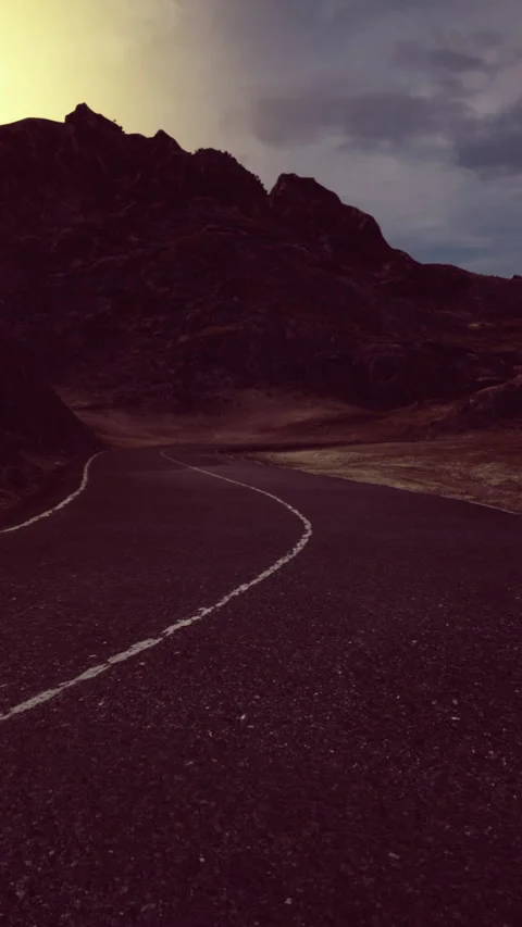 Winding road through rugged mountains under a dramatic sunset sky Stock Footage 320303295