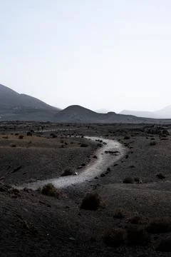 Winding rocky road through a desolate landscape with distant mountains Stock Photos