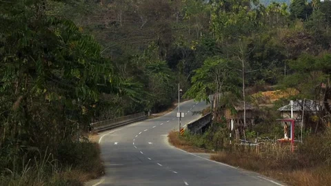 Winding rural road crossing a small bridge through forested hills Stock Footage 330702804