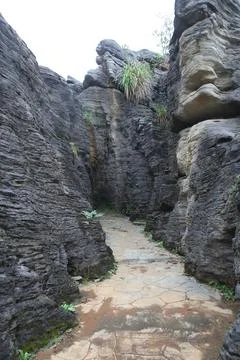 Winding stone path through a narrow gorge of towering layered dark grey roc.. Stock Photos