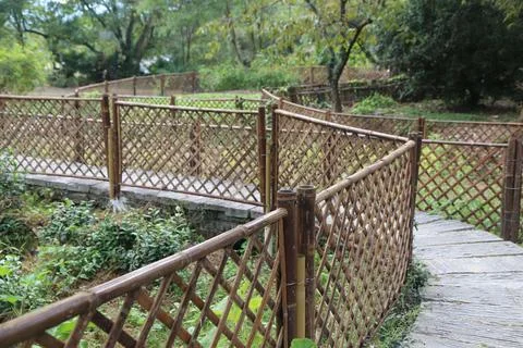 Winding stone pathway lined with a decorative woven bamboo fence through a .. Foto stock