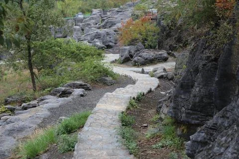 Winding stone pathway navigating through heavily layered dark karst rock fo.. Stock Photos