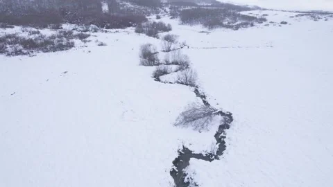 Winding stream flowing through snowy field The concept of cold Stock Footage 327465251