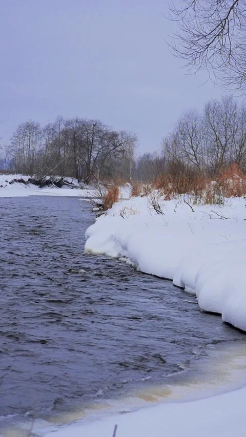 Winding Winter River with Snow-Covered Shorelines Vertical Slow Motion - Winter Stock Footage 326665740