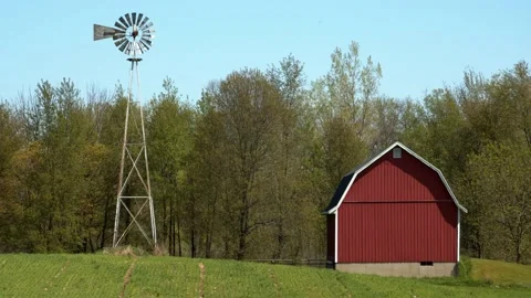Windmill and red barn in a grassy field. 4k60p Stock Footage 132435464