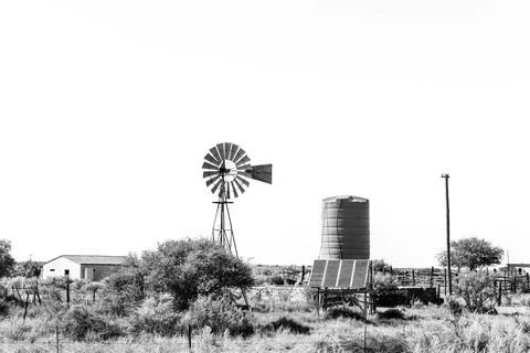 Windmill and solar panel driven water pump. Monochrome Stock Photos