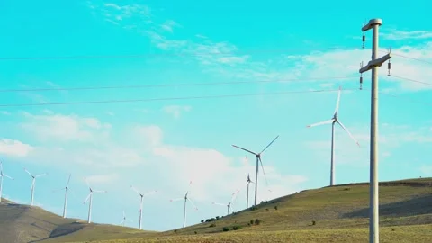 Windmill and transmission tower over hill 스톡 동영상 246366294