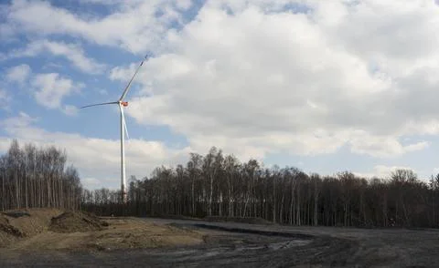 A windmill with a blue sky and clouds. A dirt road with trees in the backgrou Foto stock