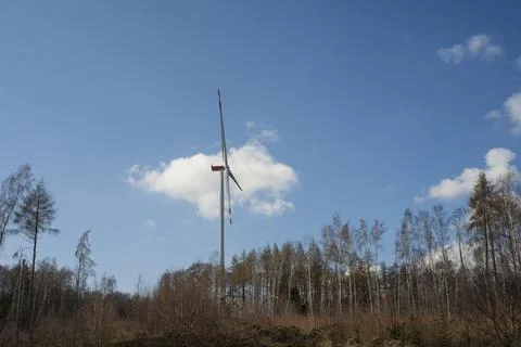 A windmill with a blue sky and clouds. A dirt road with trees in the backgrou Foto stock