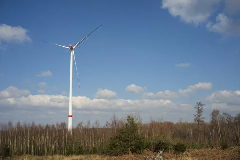 A windmill with a blue sky and clouds. A dirt road with trees in the backgrou Stock Photos