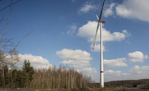 A windmill with a blue sky and clouds. A dirt road with trees in the backgrou Stock Photos
