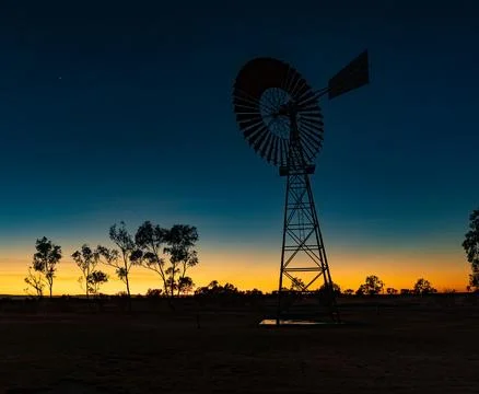 A windmill at the brink between twilight and sunset-sunrise Stock Photos