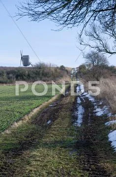 Windmill at a dirt road in springtime Stock Photos
