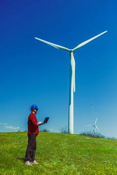 Windmill engineer checks data on laptop near wind turbines on a sunny day i.. 스톡 사진