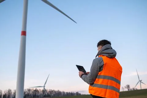 Windmill engineer does maintenance and repairs wind turbines using a tablet in Stock Photos
