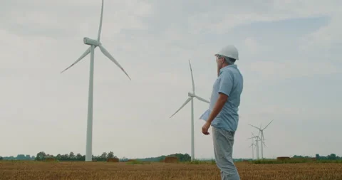 Windmill engineer in a hard hat inspects the work done while standing field. Stock Footage 209531576
