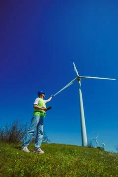 A windmill engineer inspects a wind turbine at a wind farm. The engineer stan Fotos Stock