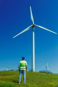 Windmill engineer observing a wind turbine on a clear day in an open field 写真素材