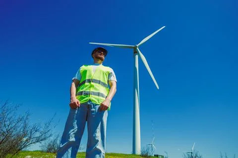 Windmill engineer stands near wind turbine under blue sky in the afternoon Foto stock