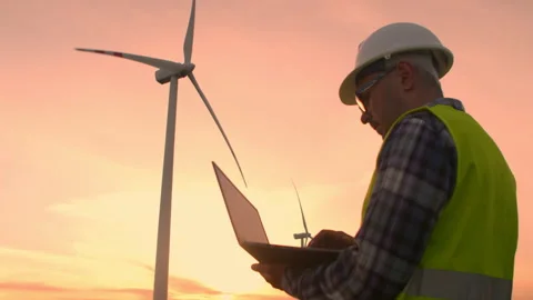 Windmill engineer watching wind turbines in operation on a laptop Stock Footage 192860604