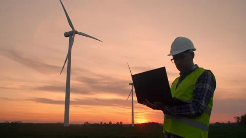 Windmill engineer watching wind turbines in operation on a laptop Stock Footage 197014885